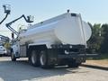 A 2008 Peterbilt 340 fuel truck with a large white tank and three axles visible from the rear angle