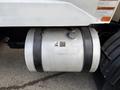 A cylindrical silver fuel tank mounted on the side of a 2010 Autocar Xpeditor truck with a black strap securing it in place