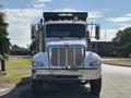 A 2015 Peterbilt 337 truck with a silver front grille and orange lights on top facing directly towards the viewer