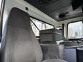 The interior of a 2010 Autocar Xpeditor featuring a black driver's seat and a compact storage box positioned on the dashboard