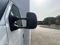 A 2008 Ford Econoline with a focus on its side mirror reflecting the surroundings