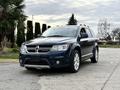 A blue 2013 Dodge Journey with a sleek design and chrome accents parked with its front angled slightly towards the camera