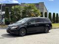A black 2014 Honda Odyssey parked, featuring a sleek design with a shiny exterior and stylish black wheels