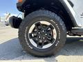 A close-up of a 2021 Jeep Wrangler's black alloy wheel with rugged All-Terrain tires prominently displayed