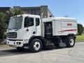 A 2012 Autocar Xpert street sweeper with a white body and red accents featuring a large water tank and a front-mounted broom for street cleaning