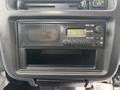 A car radio display showing the time 7:37 and FM/AM settings with a mesh speaker grille in a black dashboard console