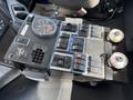 Control panel featuring various switches and gauges with a speedometer and pressure gauges on a surface within a vehicle's interior