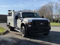 A 2009 Ford F-550 truck with a utility body and equipment rack on the back and orange warning lights on the roof