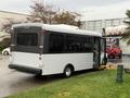 A white 2019 Chevrolet Express shuttle bus with a wheelchair lift in the back and large windows on the sides