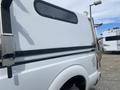A 2014 Ford F-350 SD truck with a white exterior and a fitted truck bed cap is shown from the side at an angle