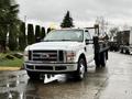 A white 2008 Ford F-350 pickup truck with a flatbed and yellow warning lights on the roof