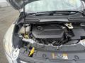 A 2014 Ford Escape engine bay showcasing the engine cover various components and fluid reservoirs
