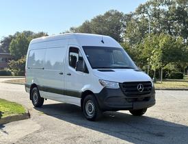 A 2020 Mercedes-Benz Sprinter van is parked at an angle showcasing its sleek white exterior and distinctive front grille design