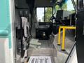Interior view of a 2020 Freightliner MT45 showing driver's seat passenger seat and controls with a yellow handrail and metal flooring