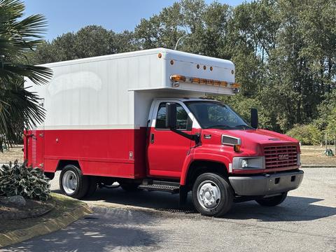 A red and white 2007 GMC C4500 TopKick truck with a boxy cargo area and side storage compartments designed for heavy-duty use