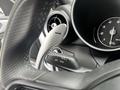 Close-up of the steering wheel and dashboard of a 2023 Alfa Romeo Giulia showing controls and a speedometer
