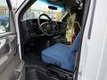 Interior view of a 2013 Chevrolet Express showing the driver's seat steering wheel and dashboard with a blue fabric seat and control panel