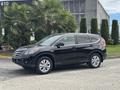 A black 2014 Honda CR-V parked on a paved surface with its side profile prominently displayed