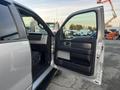 A 2014 Ford F-150 with the front passenger door open displaying the interior features and seating area