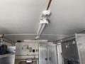 A ceiling view inside a trailer showing LED lighting and stainless steel appliances including a freezer and sink