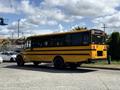 A yellow 2011 Freightliner B2 school bus with black trim and large windows parked on a street