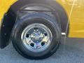 Close-up of a chrome wheel on a yellow 2015 RAM 1500 truck showcasing the tire tread and wheel design