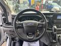 Interior view of a 2021 Ford Transit-350 featuring a steering wheel with controls and dashboard display along with gear shift and key in the ignition
