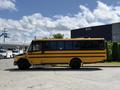 A 2011 Freightliner B2 school bus painted yellow with black stripes parked at an angle with large windows and a high roof