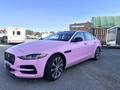A pink 2020 Jaguar XE with a sleek design featuring a distinctive grille and sporty wheels positioned at an angle