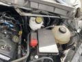 Engine compartment of a 2019 Ford Transit including battery and fluid reservoirs with various hoses and components visible