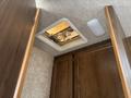 A ceiling vent with a fan in a 2018 Westland Travelaire interior with wooden cabinetry and smooth, light-colored walls