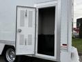 A 2012 Ford F-550 with an open side door revealing a storage compartment with a metal floor and no visible contents