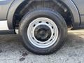 A close-up view of a silver wheel with a black tire labeled with a tread pattern designed for all-season use on a 2019 Ford Transit 350