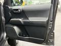 The interior door panel of a 2016 Toyota Tacoma features a black textured surface with a door handle a speaker and control buttons for windows and locks