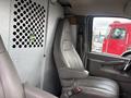 A 2022 GMC Savana driver's seat featuring a gray leather seat with armrests and a metal partition behind it