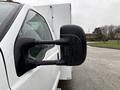 A 2000 Ford F-450 truck with a focus on the driver's side mirror showing a black and textured surface with raindrops on it