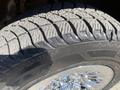 Close-up of a tire with deep tread patterns mounted on a shiny wheel from a 2013 Chevrolet Silverado 1500