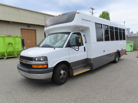 A 2020 Chevrolet Express with a white exterior, large windows, and a low-step entrance, designed for passenger transport