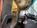 Interior view of a 2012 Ford Econoline showing the driver's seat and dashboard with controls and a doorway leading to the cargo space