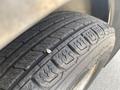 A close-up of a tire tread showing wear patterns with a small stone embedded in the rubber