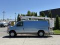A 2006 Ford Econoline van with a utility bucket lift attached to the roof parked on a driveway