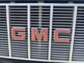 Close-up of the front grille of a 1996 GMC Top Kick featuring prominently displayed red GMC letters against a series of horizontal silver slats
