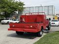 A red 2013 Ford F-550 with a flatbed and utility box in the rear parked on a lot