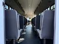 Interior view of a 2021 Ford Econoline showing rows of black seats facing forward with an aisle in the center