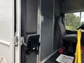 A 2018 Ford Econoline interior featuring a driver's seat next to a gray wall with a folded seat and a sign on the floor saying thank you