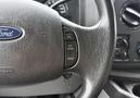 Close-up of a 2013 Ford E-350 steering wheel showing control buttons for cruise control and the Ford logo at the center