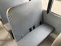 A bench seat in a 2013 International 4300 bus with gray vinyl upholstery showing some wear and tear