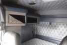 Interior of a 2015 Kenworth T660 showing a gray quilted wall design and a single leather seat with a storage compartment above