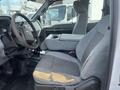 Interior of a 2014 Ford F-250 SD featuring a gray driver's seat with a worn section and a central console between the seats