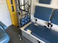 A 2011 Chevrolet Express interior featuring blue seats a yellow door and a stretcher secured with straps